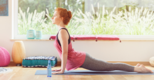 Persoana practică yoga pe o saltea cu o sticlă de apă lângă