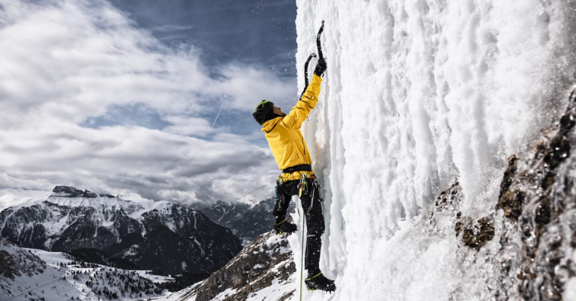 Alpinist urcând pe un perete de gheață cu echipament de alpinism