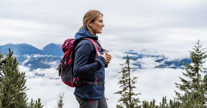 O persoană cu un rucsac merge pe un traseu montan