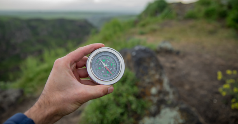O persoană ține un compas în mână în aer liber