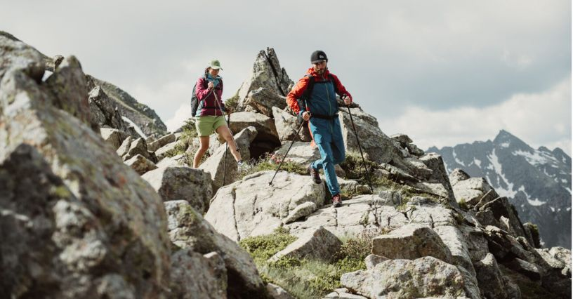 Persoane merg pe un teren stâncos în echipament de drumeție