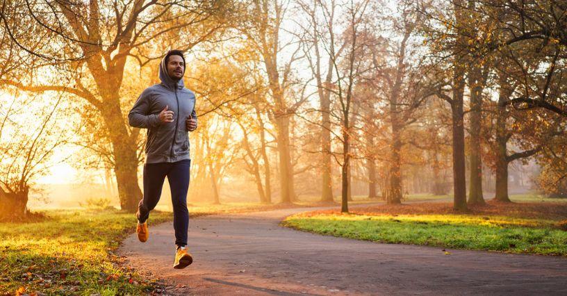 Bărbat aleargă pe o potecă în parc dimineața devreme