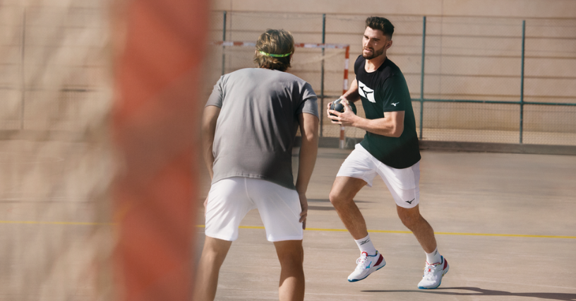 Doi bărbați joacă handbal pe un teren în aer liber