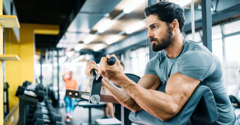 Bărbat antrenându-se la un aparat de fitness în sală