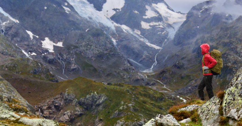 O persoană cu echipament de drumeție admiră peisajul montan