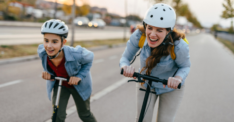 Persoane pe trotinete poartă căști de protecție