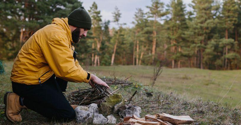Persoană pregătind focul în aer liber, ideal pentru echipament de camping