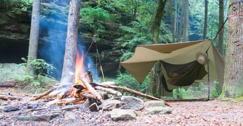 Tabăra cu foc și hamac sub copaci într-o pădure