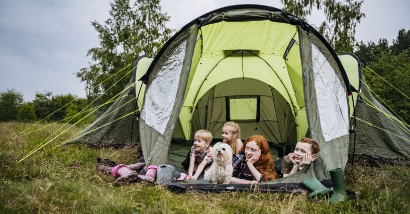 O familie relaxează într-un cort spațios de șase persoane, într-o poiană